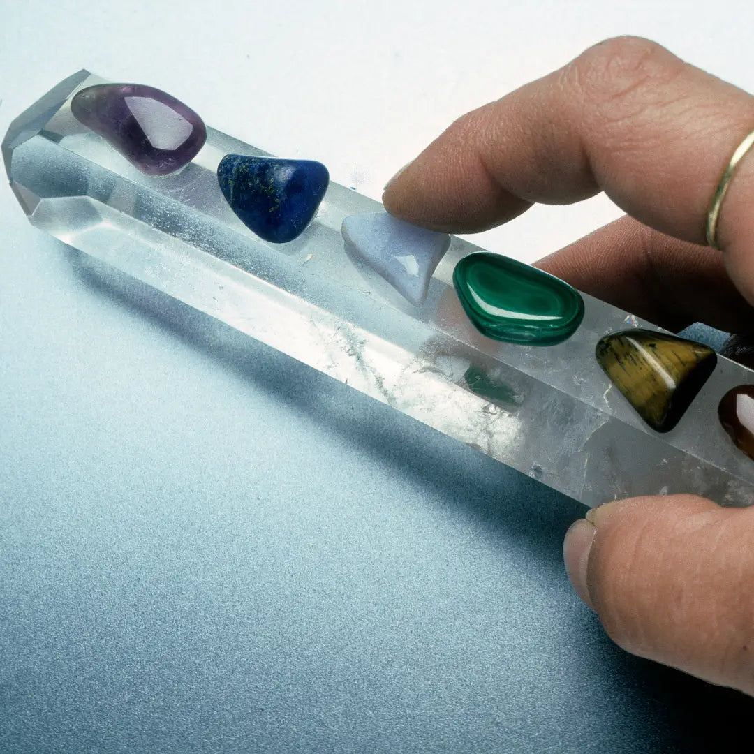 Comment choisir votre Pierre : Une main tenant un cristal avec différentes pierres précieuses pour la lithothérapie.