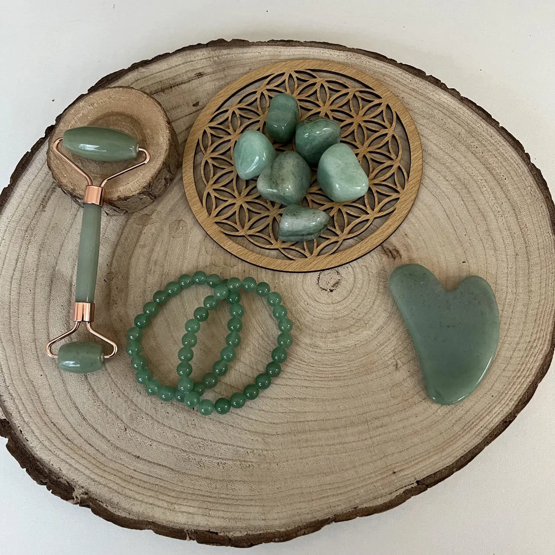Ensemble de pierre aventurine verte comprenant un rouleau facial et des bracelets sur un plateau en bois