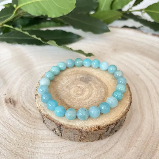 Bracelet Amazonite Naturel en pierres rondes bleu clair sur une base en bois.