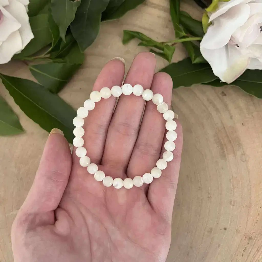 Bracelet en Nacre Naturelle Aura de Roche composé de perles blanches rondes tenues dans une main