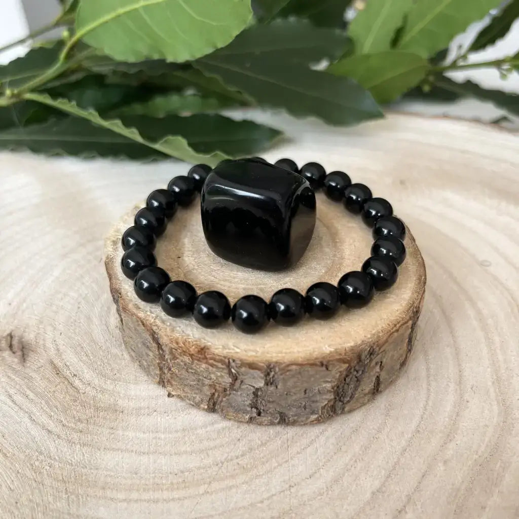 Bracelet & Pierre Obsidienne avec perles noires brillantes sur un support en bois naturel