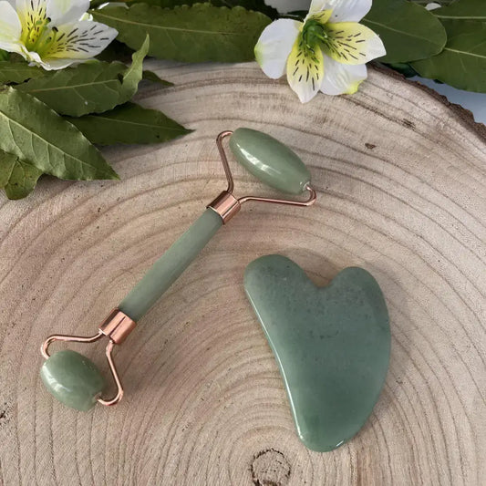 Gua sha et Rouleau de massage Aventurine verte avec poignées en cuivre sur une planche en bois