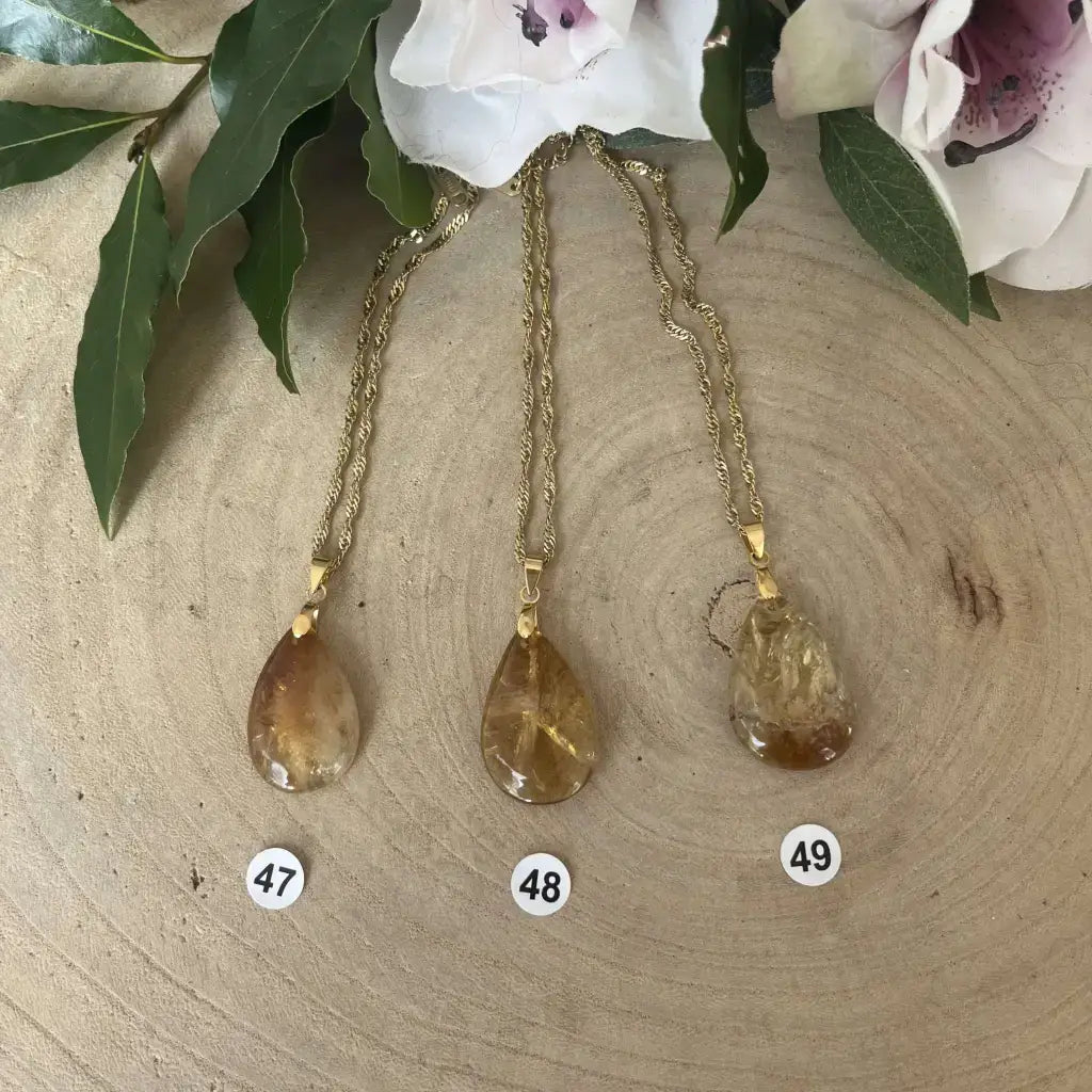 Collier avec Pendentif Citrine pendants en forme de goutte sur chaîne dorée avec fleurs en arrière-plan