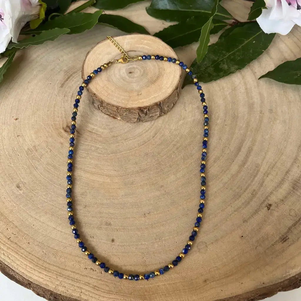 Collier Eden Lapis Lazuli en acier inoxydable avec perles bleues et dorées sur un fond en bois naturel