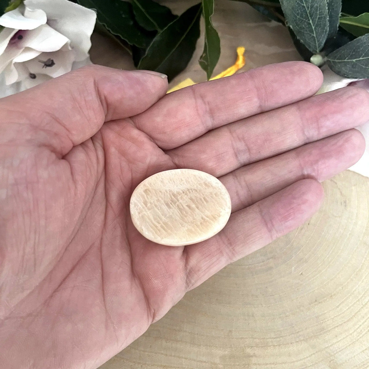 Galet anti-stress en pierre de lune beige tenu dans la main