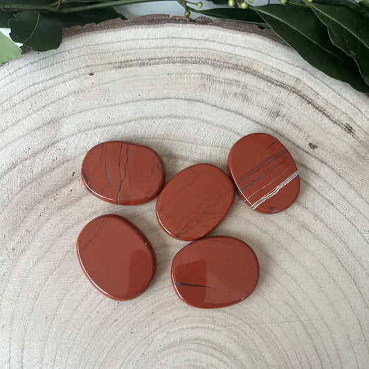 Galet Plat Jaspe Rouge Aura de Roche lot de cinq galets plats polis en jaspe rouge posés sur une tranche de bois