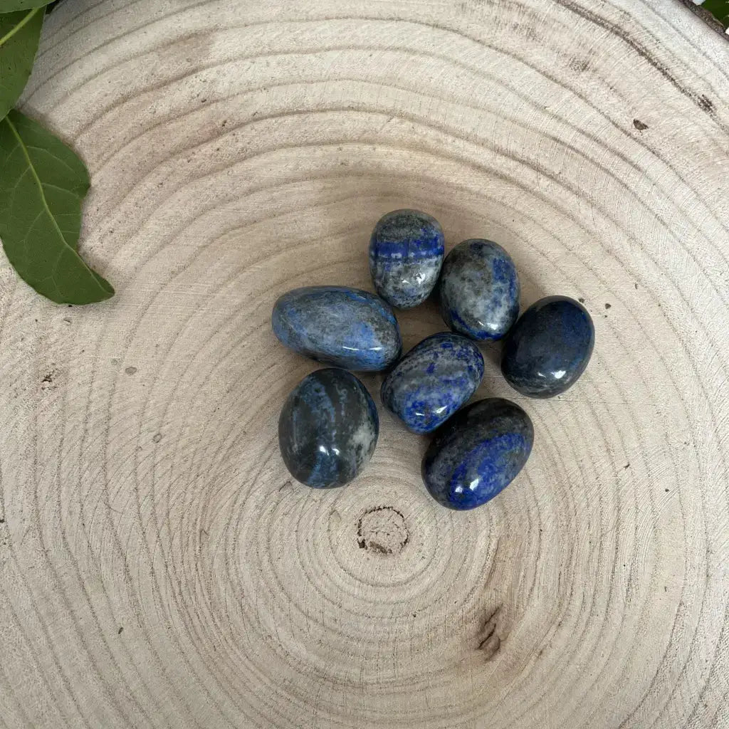 Lapis Lazuli Pierre Roulée disponibles en différentes teintes de bleu sur un plateau en bois naturel
