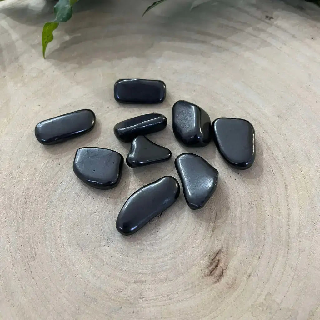 Mini Pierre Roulée Shungite en forme unique sur un fond en bois naturel, pierre protectrice idéale.