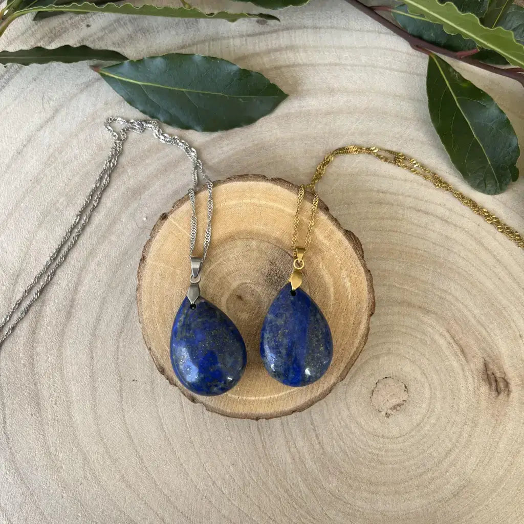 Pendentif en Lapis Lazuli en forme de goutte, suspendu sur chaînes argentée et dorée sur un fond en bois
