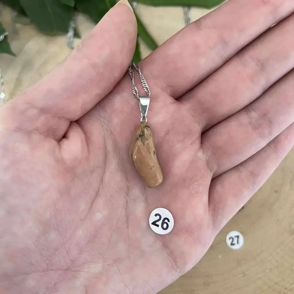 Pendentif Jaspe Léopard en pierre naturelle avec un design élégant, présenté sur une main
