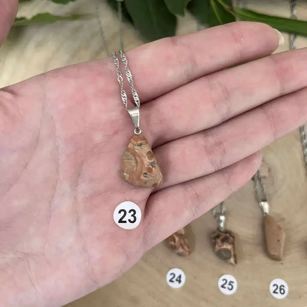 Pendentif Jaspe Léopard en pierre naturelle, suspendu sur une chaîne en argent, posé sur une main