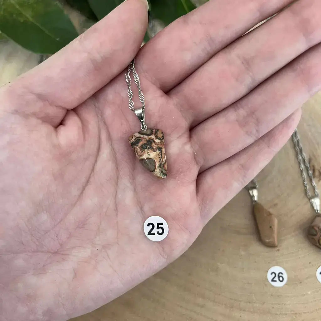 Pendentif Jaspe Léopard en pierre naturelle, suspendu à une chaîne en argent, présenté dans une main