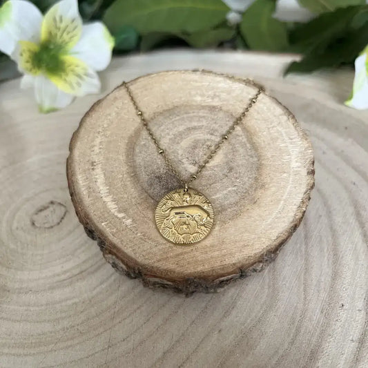 Pendentif Taureau avec Pierre de Pouvoir sur une chaîne dorée, présenté sur un suport en bois naturel