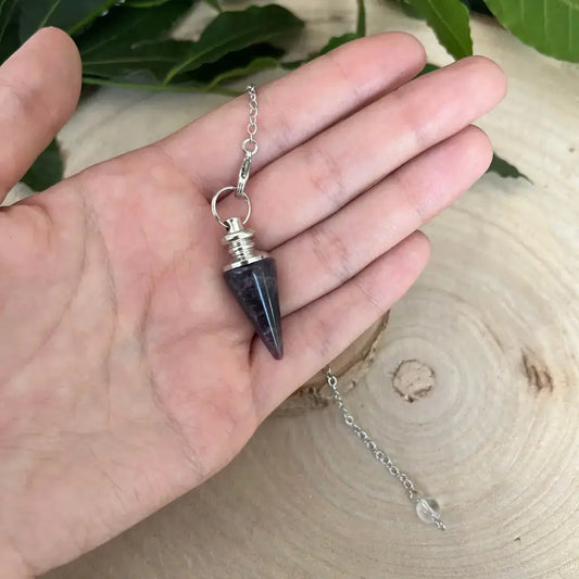 Pendule en Améthyste Aura de Roche petit pendule conique en pierre violette avec chaîne argentée tenu à la main