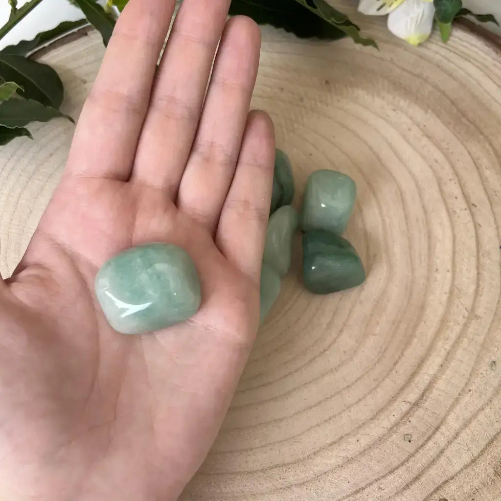 Pierre Roulée Aventurine Verte posée dans une main sur un support en bois naturel