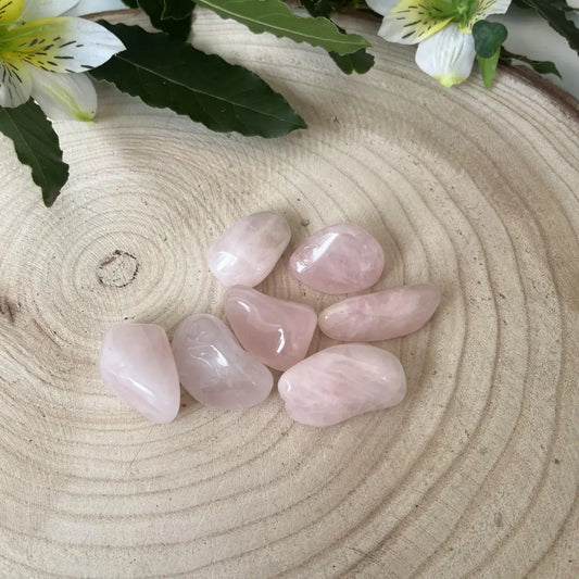 pierre roulée quatz rose posée sur rondin de bois