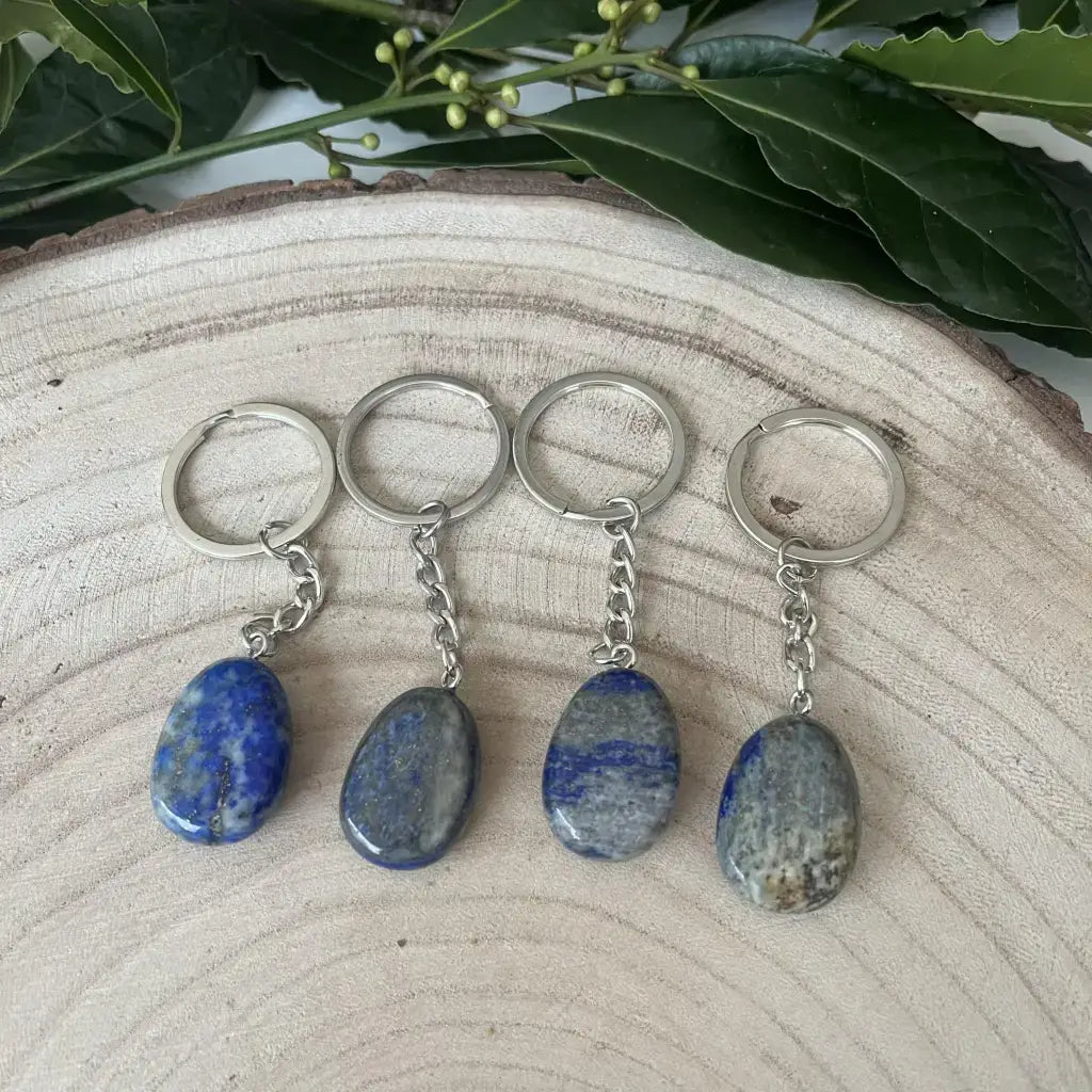 Quatre porte clé Lapis Lazuli Naturel avec des pendentifs en pierre polie sur un fond en bois