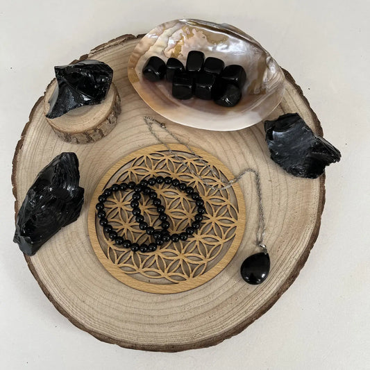 Affichage de la Pierre d'Obsidienne Noire entourée de bijoux et de minéraux sur un plateau en bois