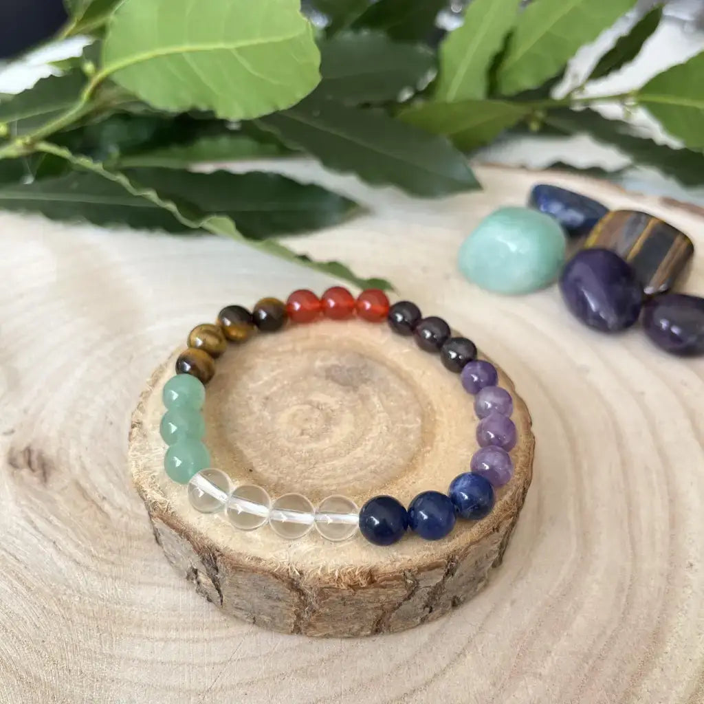 Bracelet 7 Chakras en pierres naturelles avec des perles colorées sur un support en bois