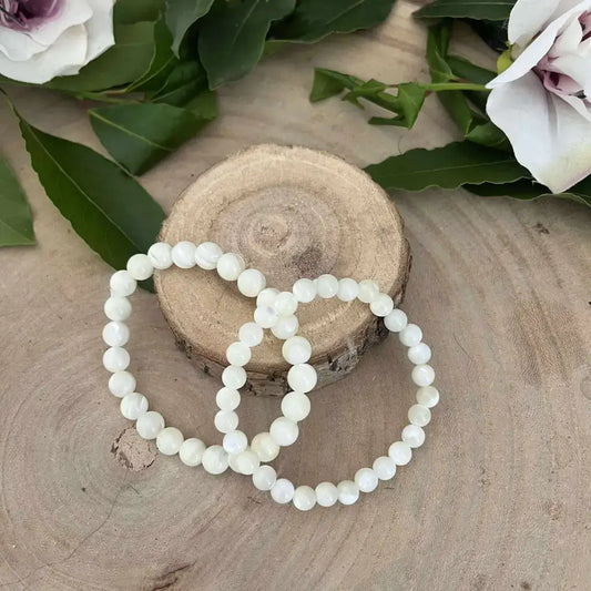 Bracelet en Nacre Naturelle Aura de Roche perles blanches rondes sur fond bois clair