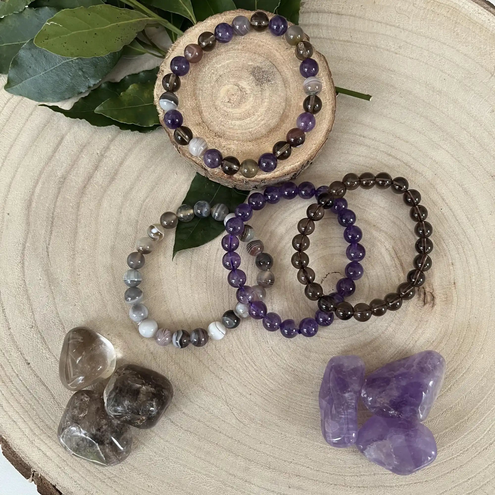 Collection de bracelets en cristal et de pierres précieuses en teintes violettes et grises.