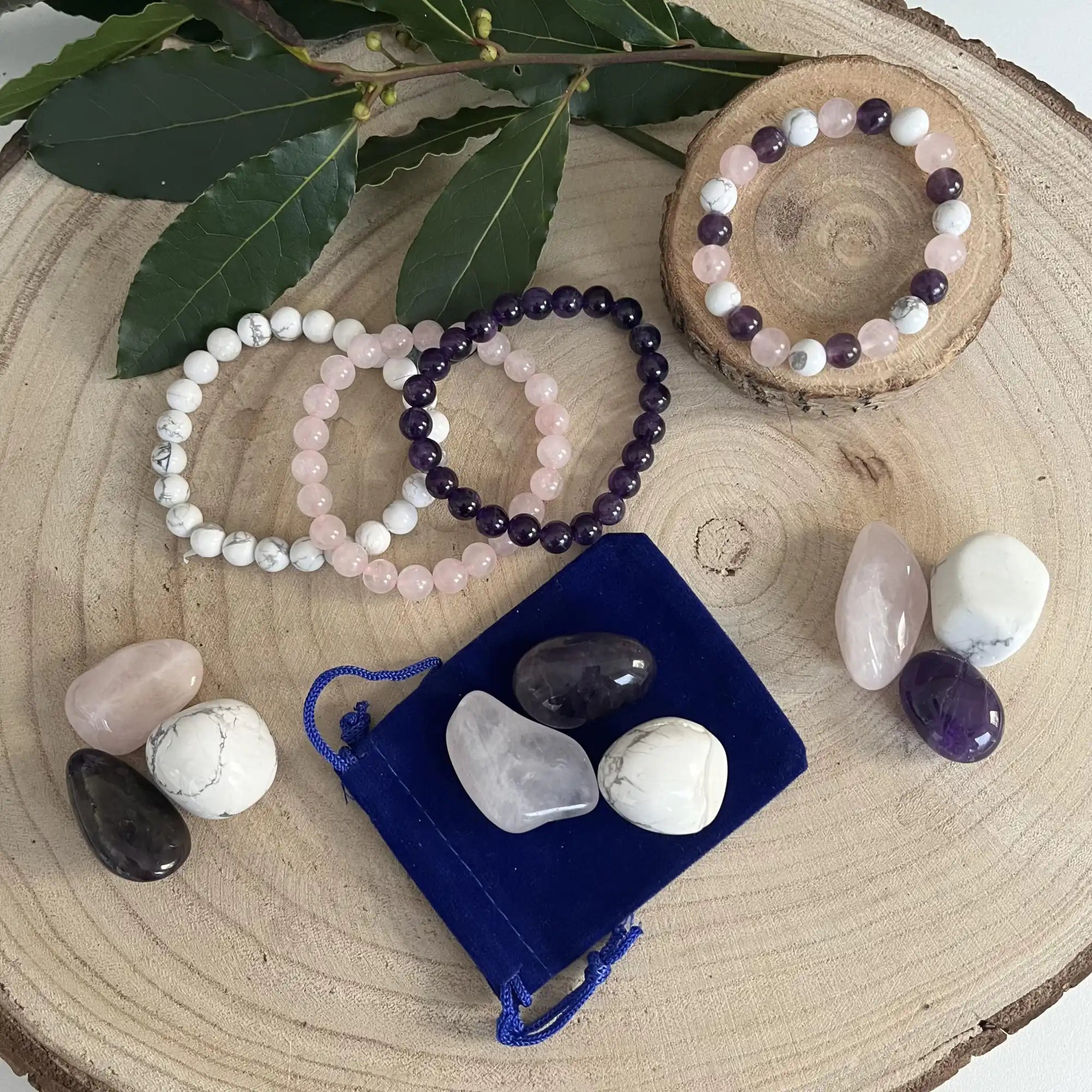 Collection de bracelets en cristal et de pierres de guérison disposés avec un sachet en velours bleu.
