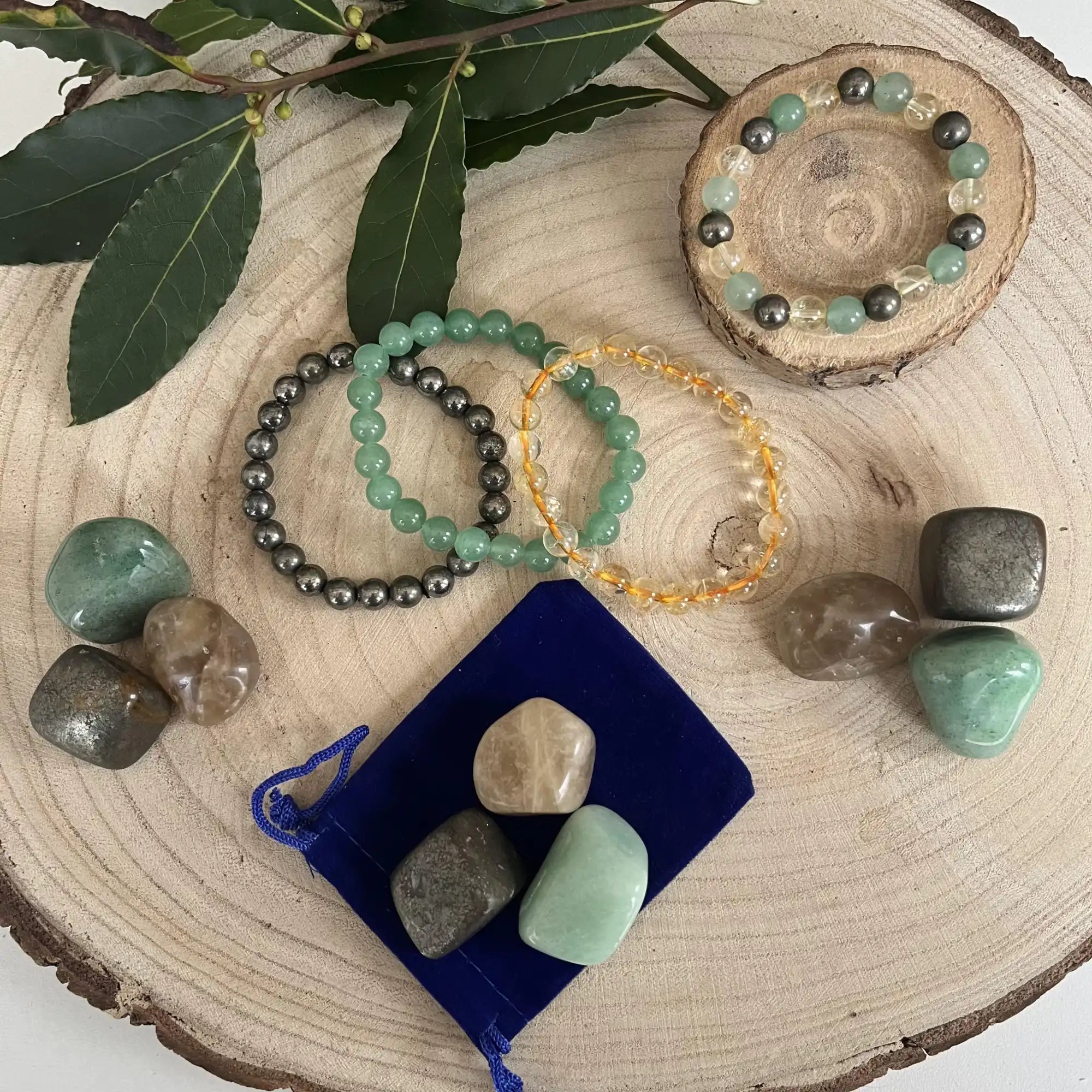 Collection de bracelets en cristal et de pierres de guérison disposés sur une tranche de bois.
