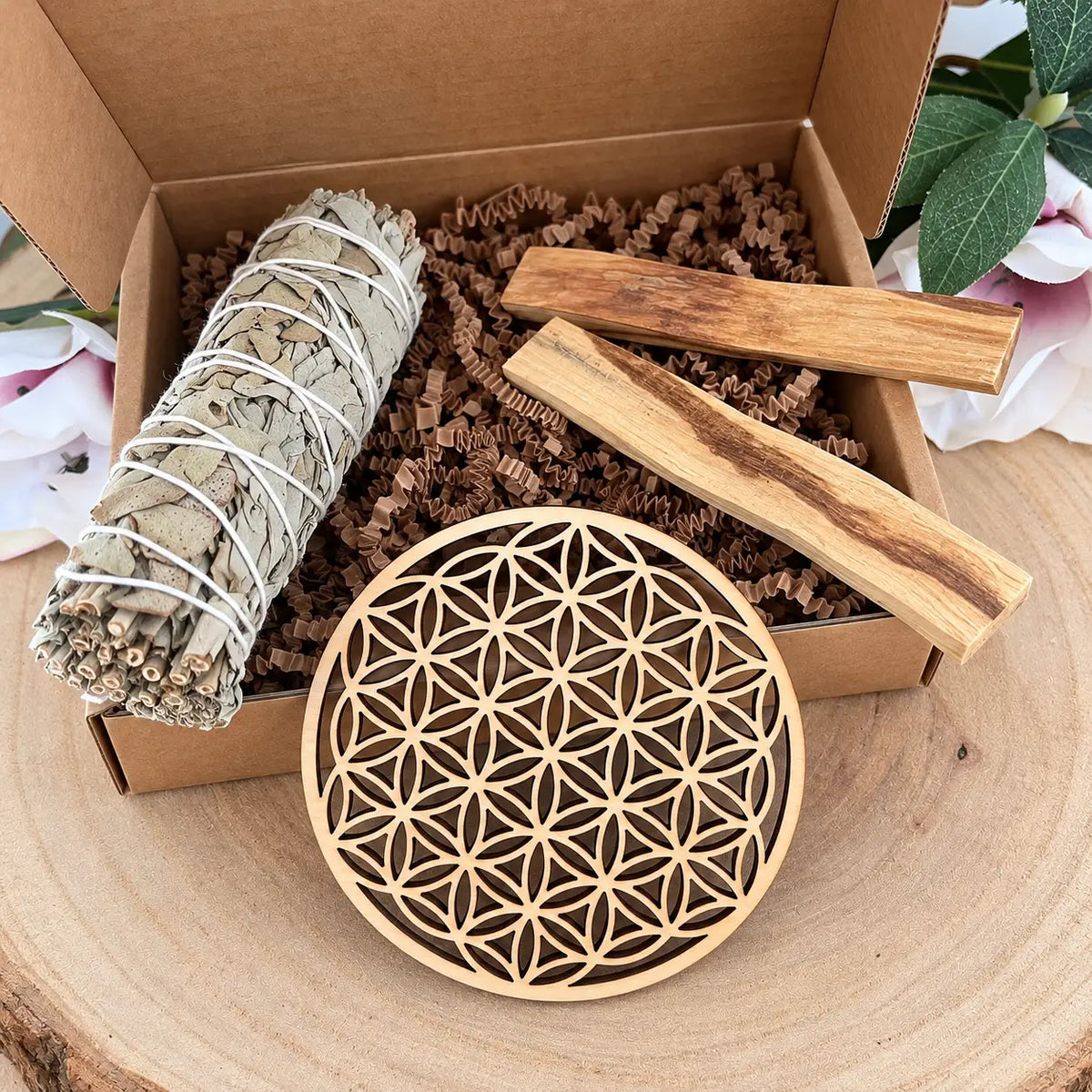 Kit rituel ouvert avec sauge blanche, palo santo et fleur de vie en bois posée devant la boîte