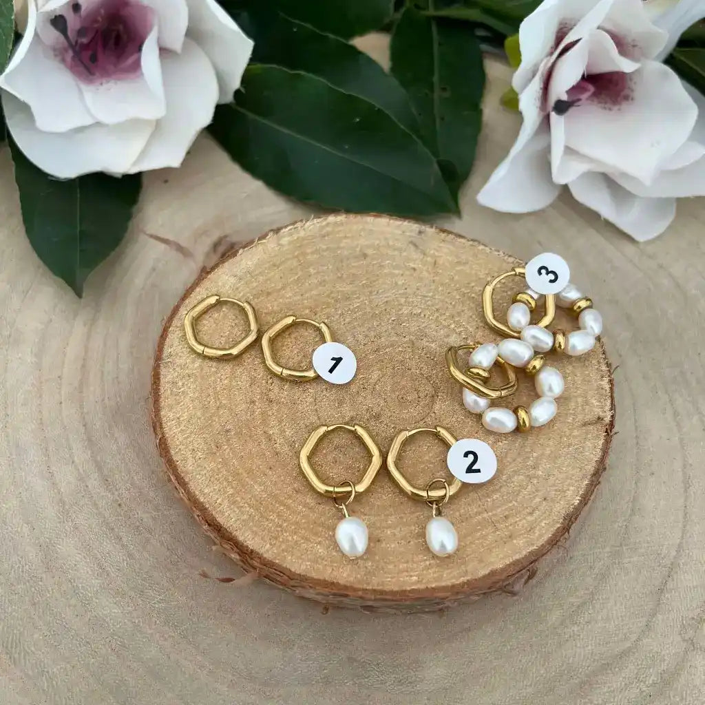 Quatre paires de boucles d'oreilles en or en forme d'anneaux, deux avec des perles pendantes et deux avec des perles enfilées.