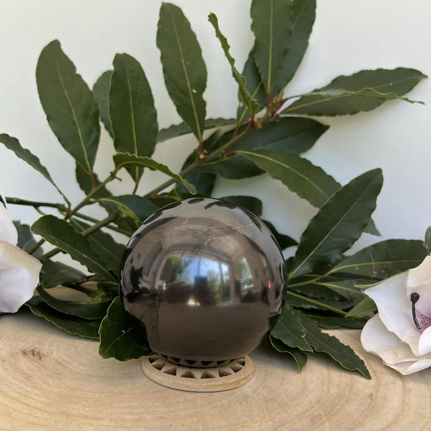 Sphère en shungite naturelle polie gris foncé sur socle en bois pour protection et ancrage naturel